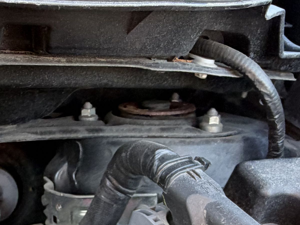 The front strut top of a grey car, photographed from the engine bay