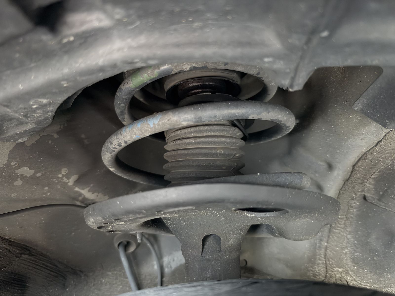 A front suspension strut and coil spring, seen from below inside the wheel arch