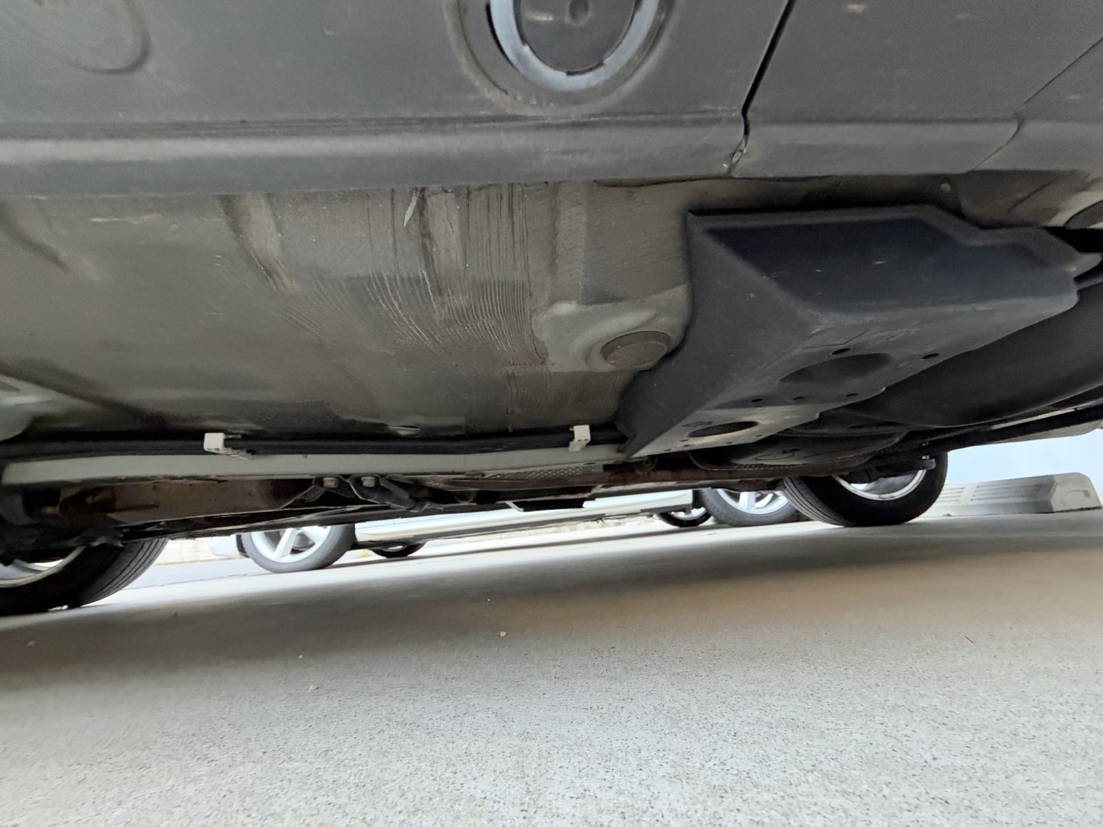 The underside of a grey car photographed from ground level, looking along the side of the car