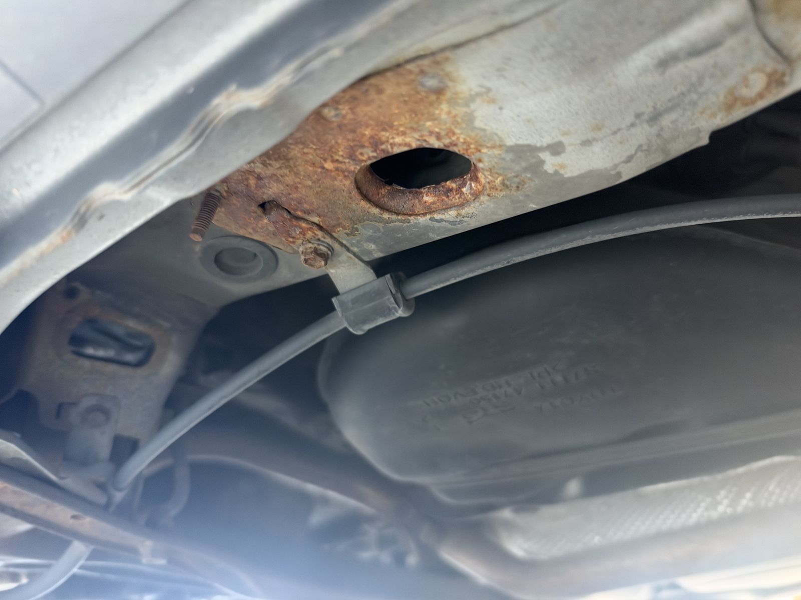 A rusty section of the underside of a car, photographed from below