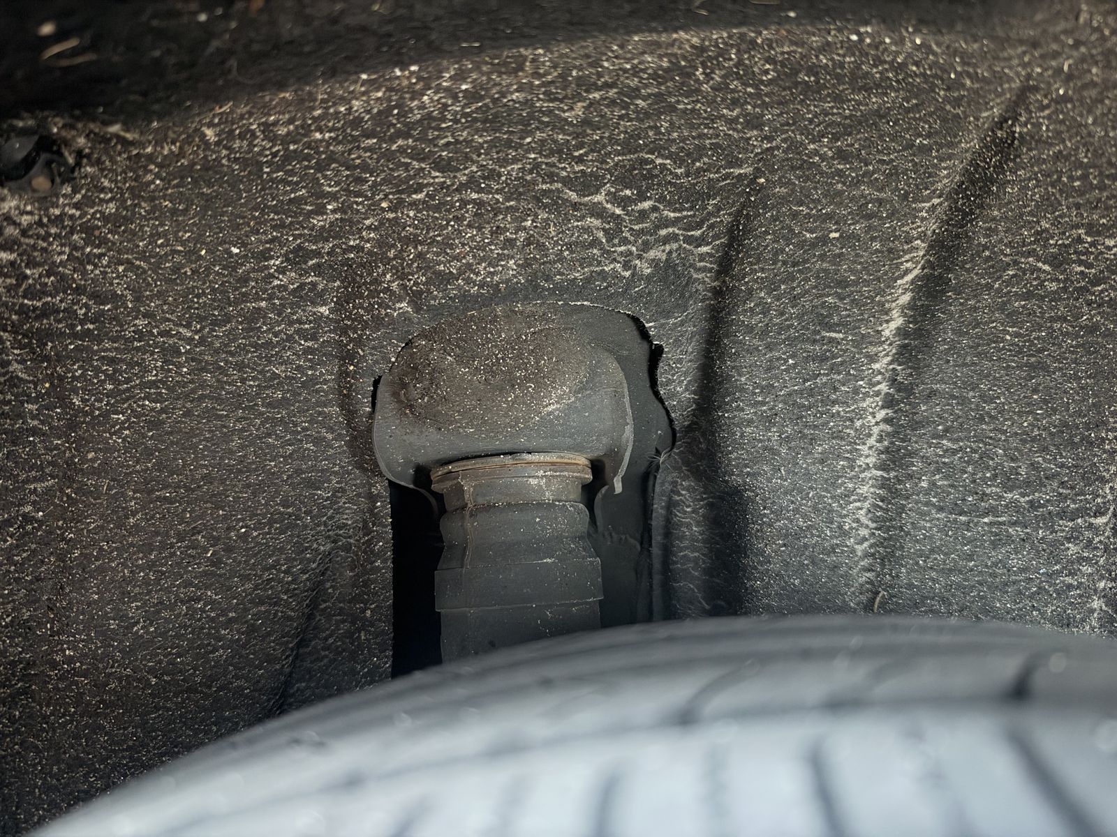 The top of a suspension strut inside a wheel arch, seen from below